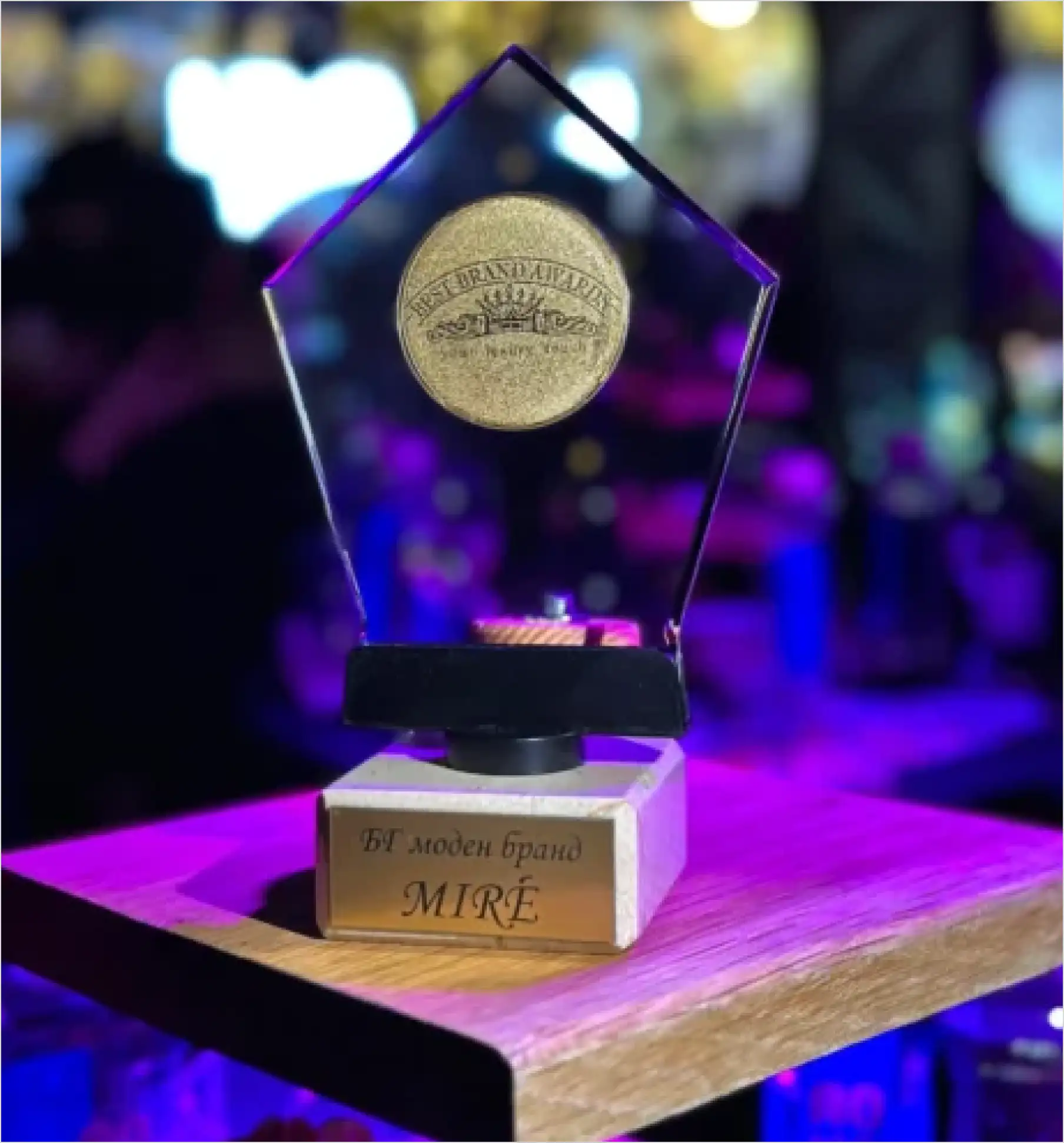 A glass MIRÉ award trophy lit on a plinth at an evening event